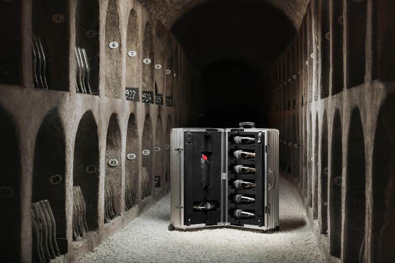 valigia di alluminio aperta con bottiglie di champagne in una cantina