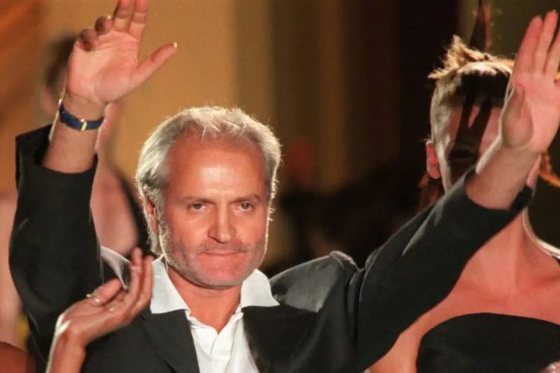 Un ritratto di Gianni Versace con i capelli grigi e un'espressione composta, in una posa elegante e sicura.
