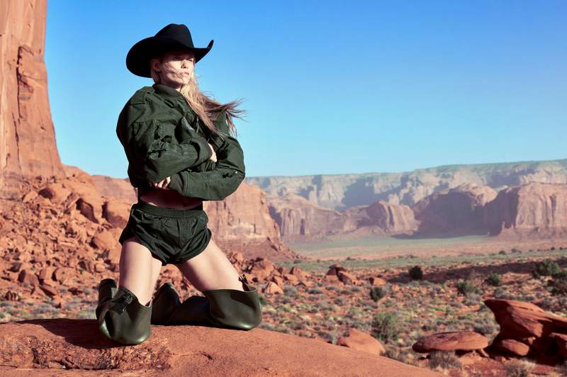 Modella nel deserto con outfit tecnico verde scuro firmato Haider Ackermann per Canada Goose, cappello da cowboy, ambientazione rocciosa e selvaggia, collezione Snow Goose SS25
