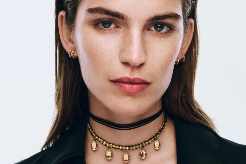 Una modella indossa un choker con pendenti e orecchini a cerchio della nuova collezione di gioielli Dodo Sigillo, con uno stile elegante e contemporaneo