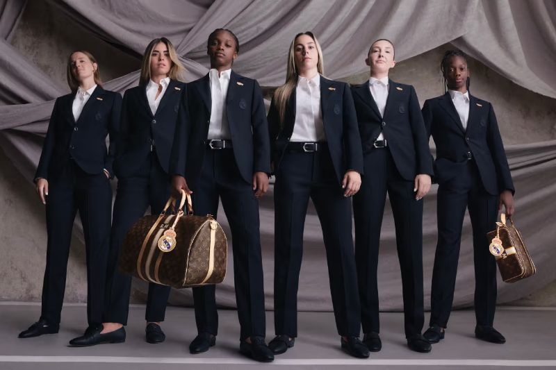 Sei giocatrici della squadra di calcio femminile del Real Madrid posano in divise formali Louis Vuitton, con blazer scuri e camicie bianche, tenendo borse a marchio Louis Vuitton