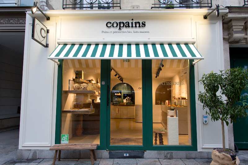 Panificio Copains a Parigi, con insegna e tenda a righe verdi e bianche.