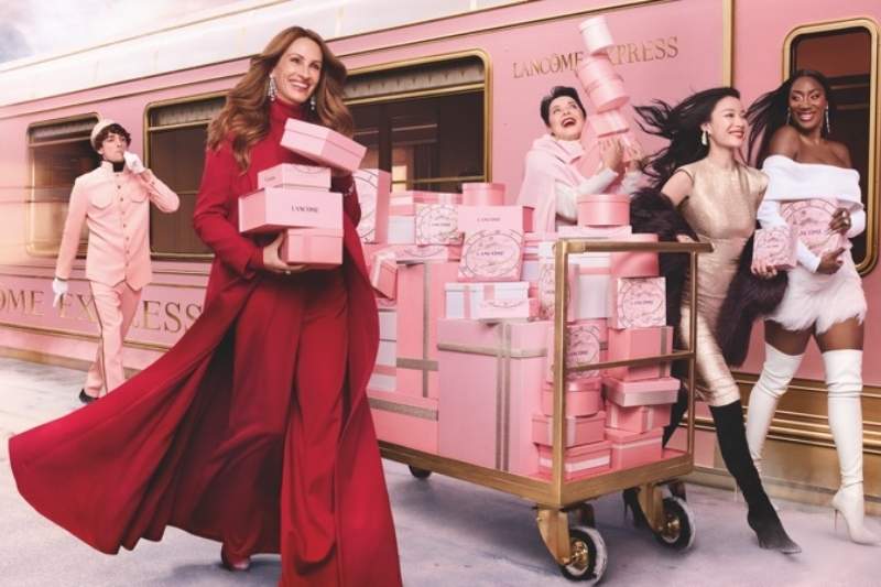 Julia Roberts con un abito rosso a bordo del Lancôme Express insieme a Aya Nakamura, Ni Ni e Isabella Rossellini tra pacchi regalo rosa e oro