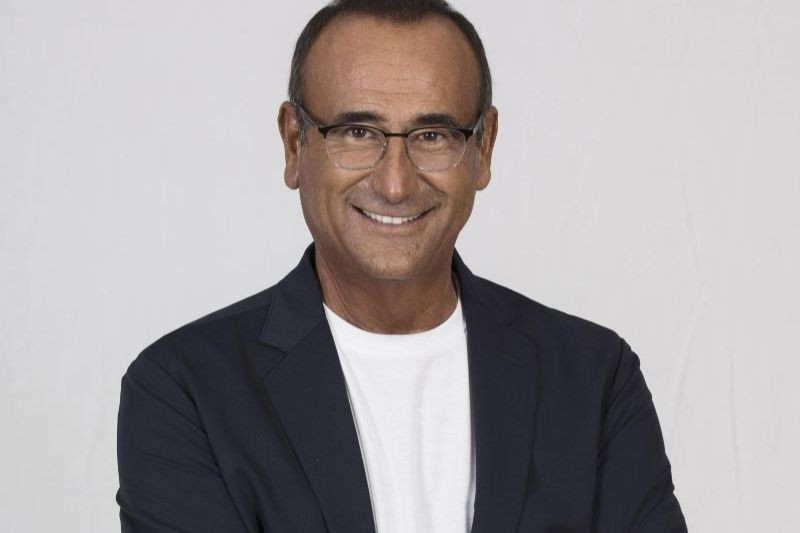 Carlo Conti sorride in un ritratto ufficiale: oggi ha presentato le novità di Sanremo 2026