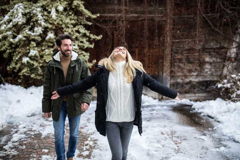 Coppia adulta cammina sulla neve in un contesto di montagna tranquillo, ideale per una vacanza adults only in Alto Adige
