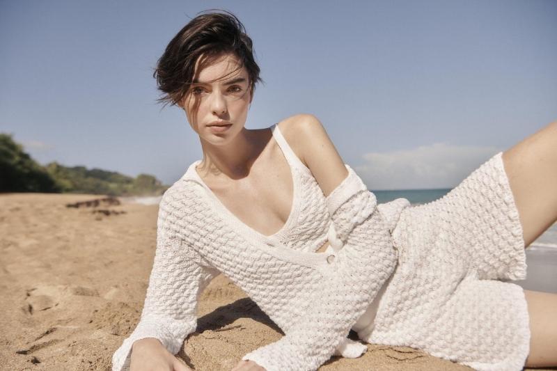 Modella sulla spiaggia con completo in maglia bianca Falconeri Sea Echos Estate 2026 ispirato alle texture delle conchiglie.