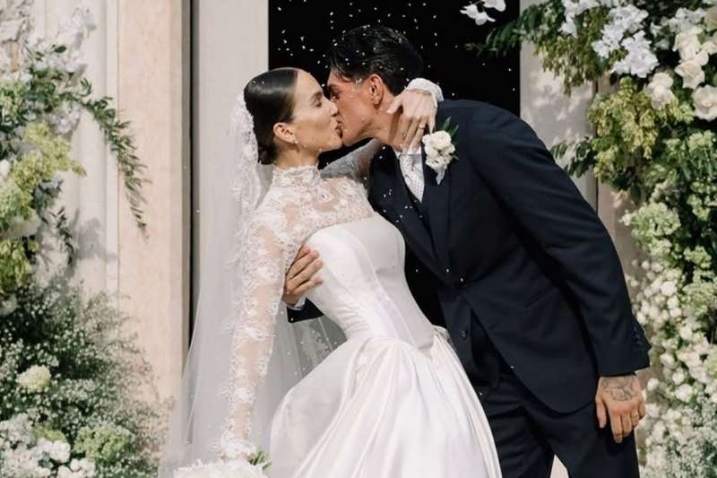Paola Di Benedetto e Raoul Bellanova si baciano all'uscita della chiesa dopo il matrimonio. La sposa indossa un abito Emé con velo in pizzo e gioielli Damiani.