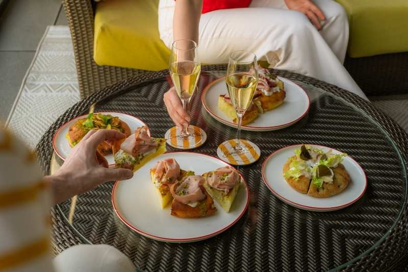 Aperitivo con calici di vino e piatti gourmet servito sulla terrazza rooftop dell’Excelsior Hotel Gallia a Milano
