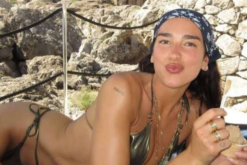Dua Lipa indossa una bandana nera con stampa paisley durante una giornata estiva al mare