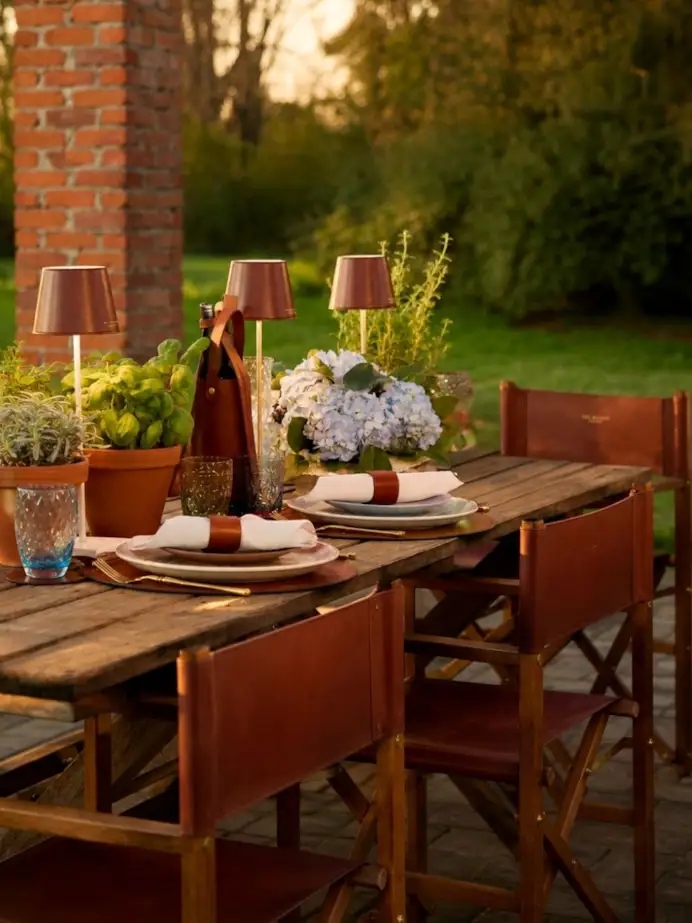 Tavola da esterno apparecchiata con accessori in pelle della collezione The Bridge Home Decor