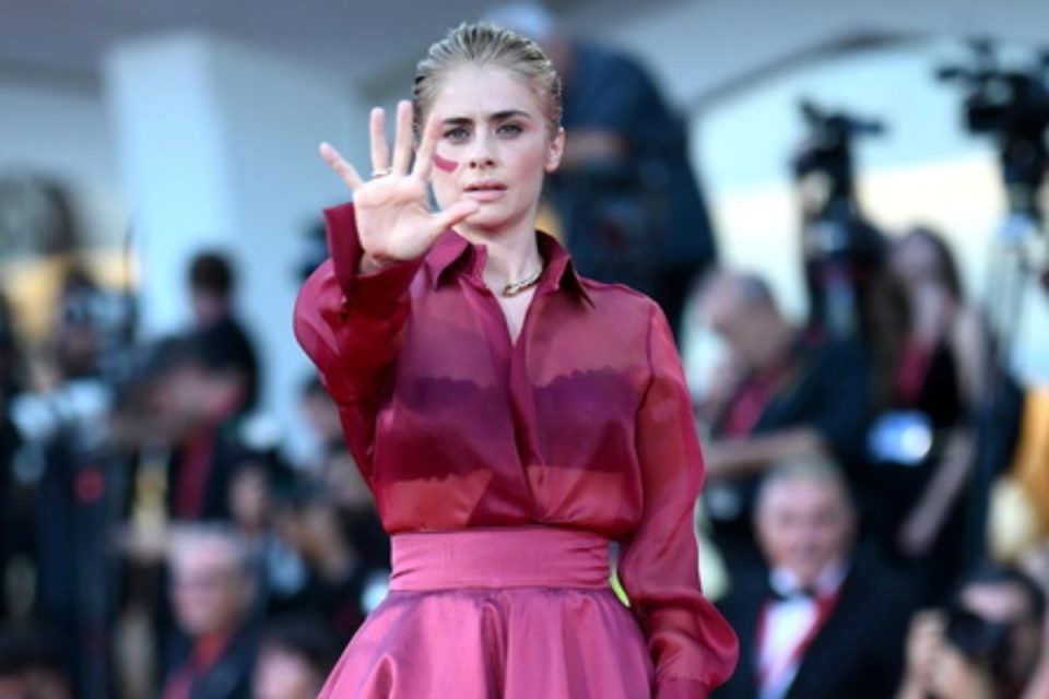 Greta Scarano sul red carpet di Venezia 83 con un segno rosso sul viso contro la violenza sulle donne