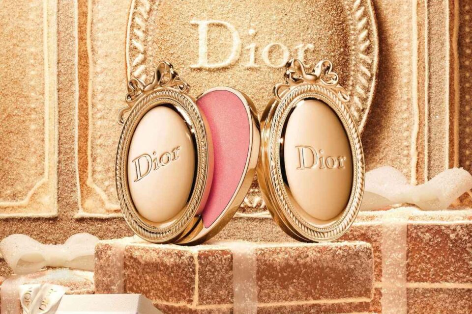 Dior Médaillon Lip Balm Holiday 2026, il balsamo labbra rosa racchiuso in un medaglione dorato con fiocco decorativo.